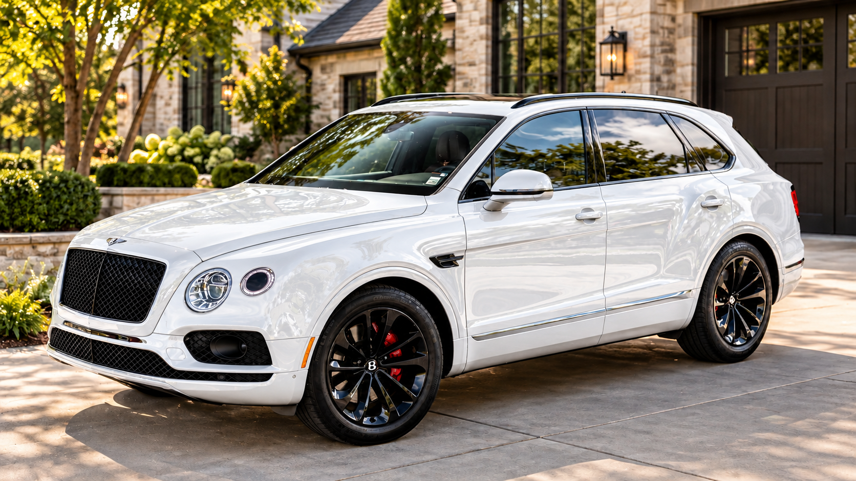 White Bentley SUV parked on a sunlit driveway outside a stone home