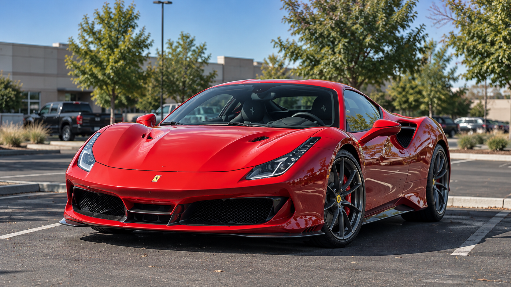 Glossy red Ferrari parked in a sunlit commercial parking lot